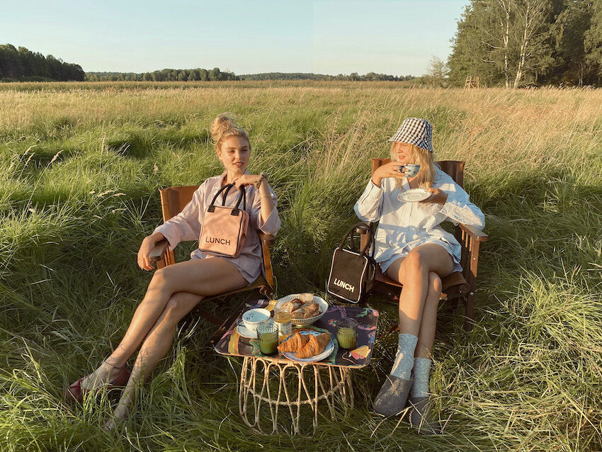 Two girls bringing their black and pink lunch boxes, enjoying their breakfast picnic