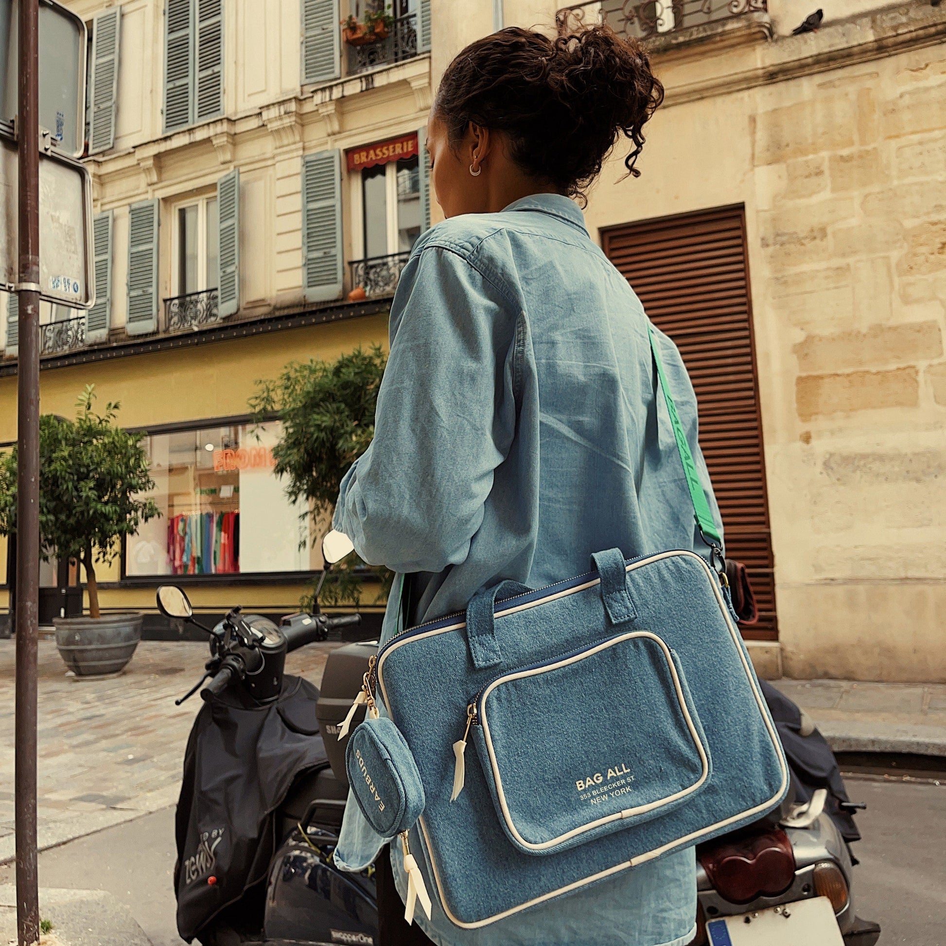 Bag-all Denim Laptop Case 13" with convenient charger pocket and handle, shown on person with scooter in urban setting, featuring stylish blue design and practical storage