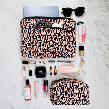 Bag-all Toiletry Pouch Love Pattern in pink and black with makeup essentials, sunglasses, and laptop flatlay on marble surface showing eco-friendly travel organization