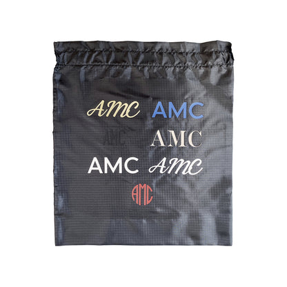 Bag-all Personalized Vinyl Bag showing multiple AMC monogram styles in different fonts and colors on black recycled nylon fabric, demonstrating personalization options