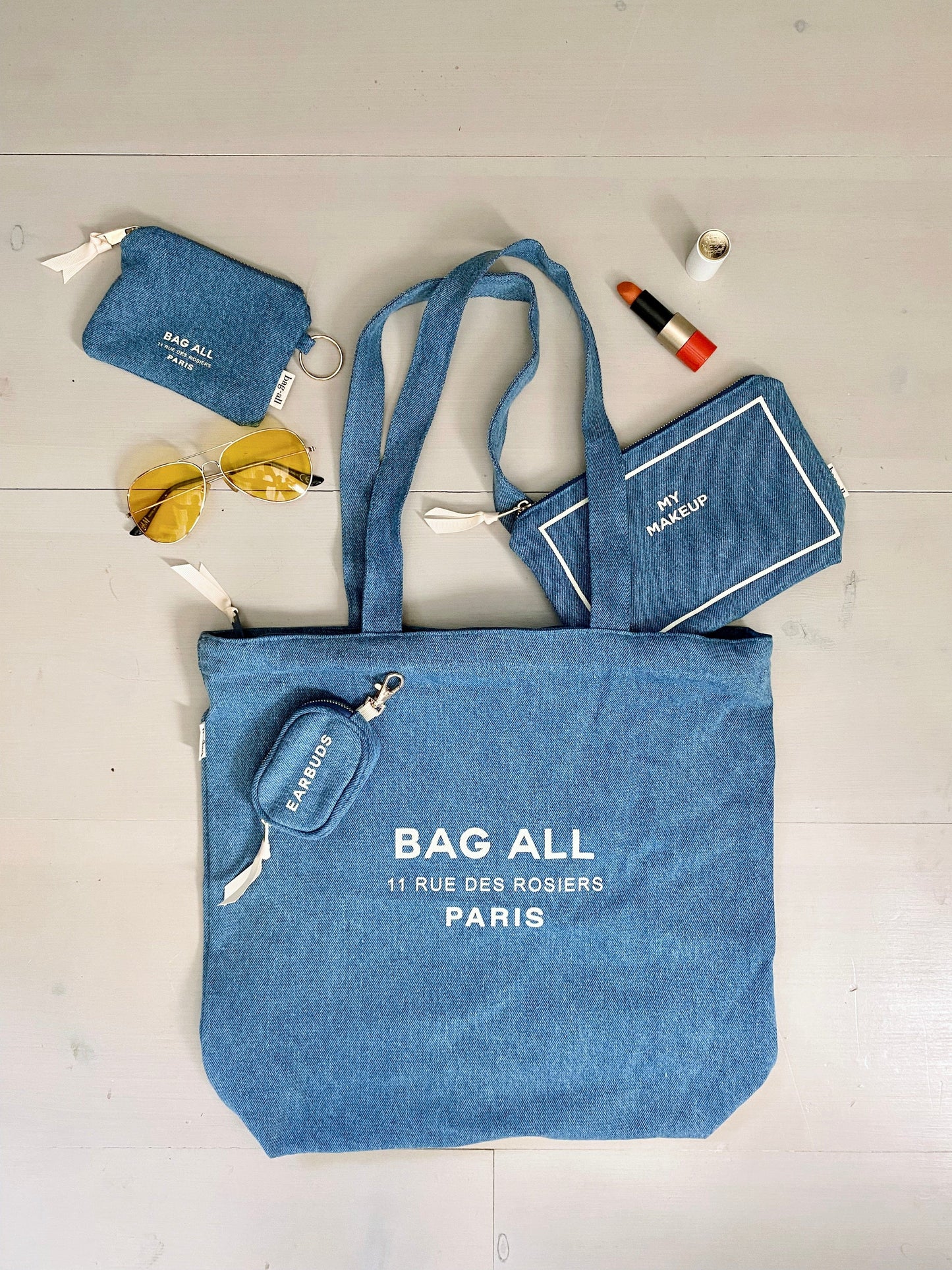 Bag-all My Makeup Pouch in denim blue with waterproof lining, shown with matching tote bag, sunglasses and lipstick. Perfect for organizing beauty essentials.