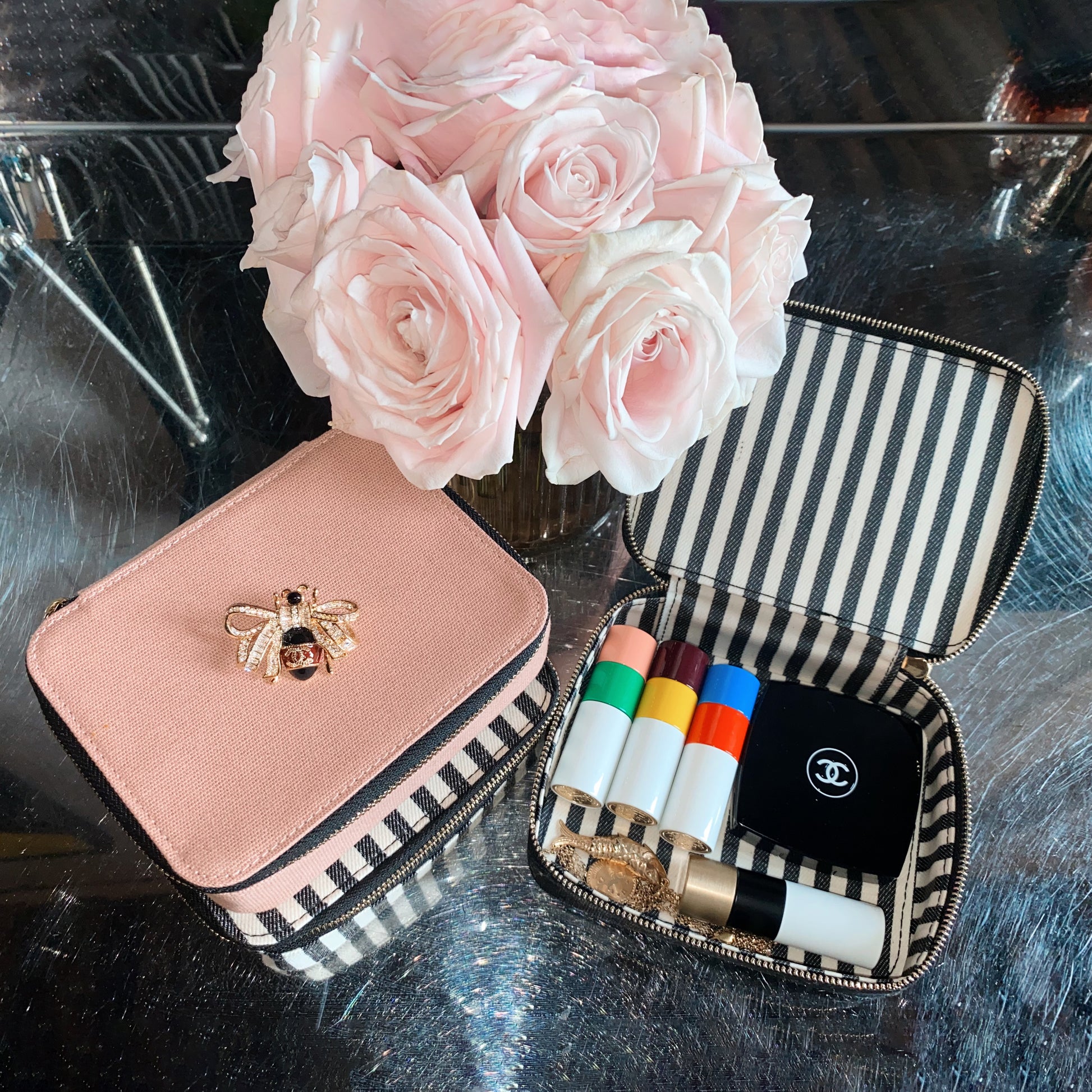 Bag-all Cosmetics/Trinket Box in black and pink with striped lining, gold bee embellishment, and convenient storage for makeup essentials, shown with pink roses