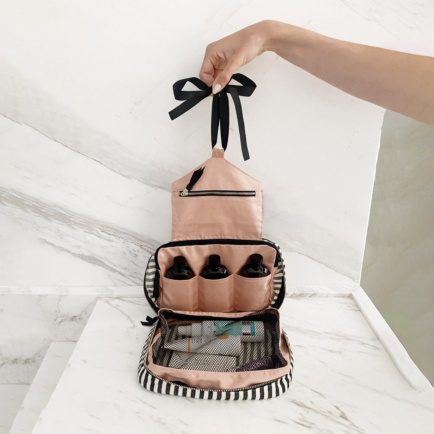 Bag-all Folding/Hanging Toiletry Case in striped cotton with three compartments, black bow, and hanging ribbon. Features pink and striped design with mesh pocket and multiple storage sections.