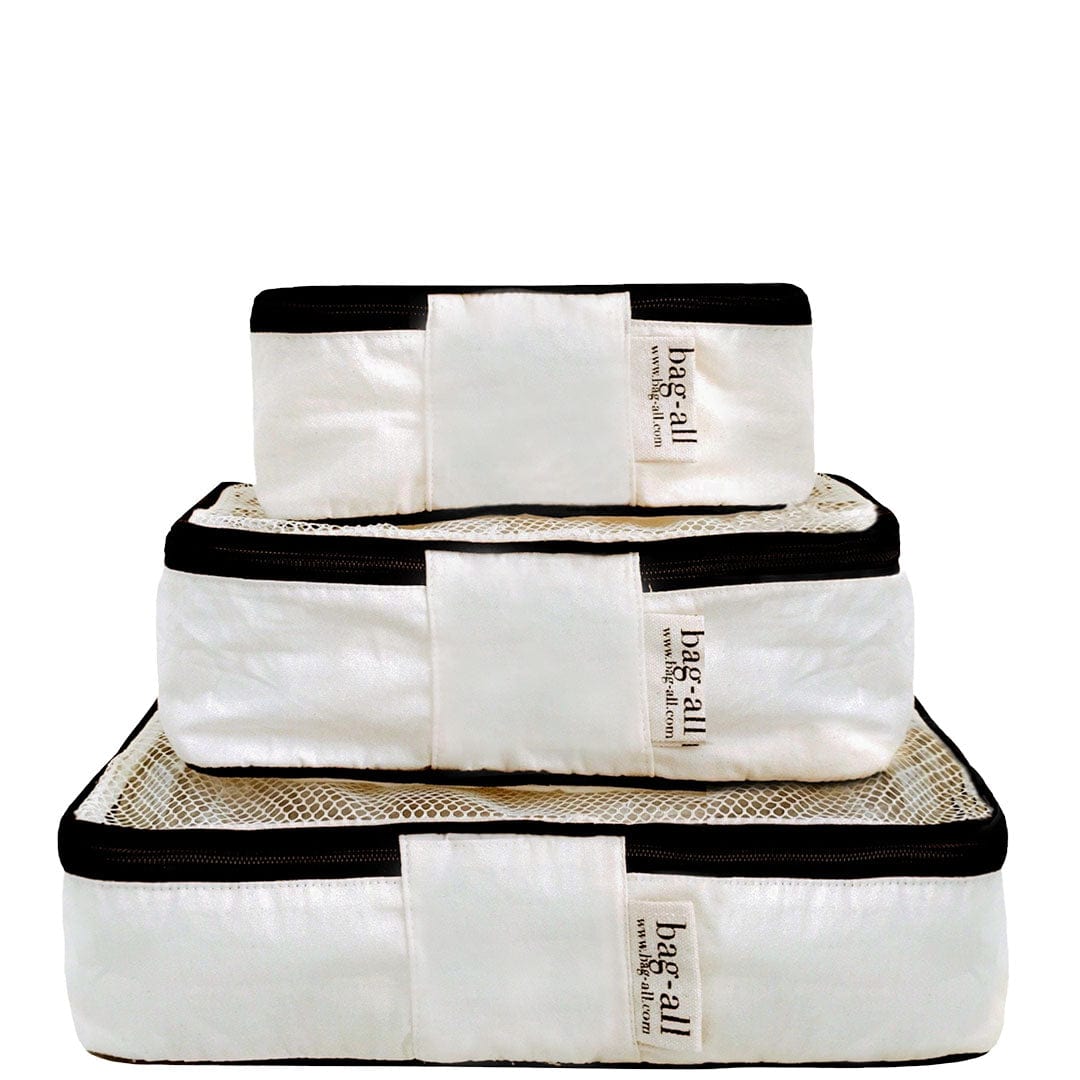 Bag-all Weekend Essential Packing Set 4-Pack in cream - three premium cotton packing cubes and pouches with black trim, stacked to show varying sizes