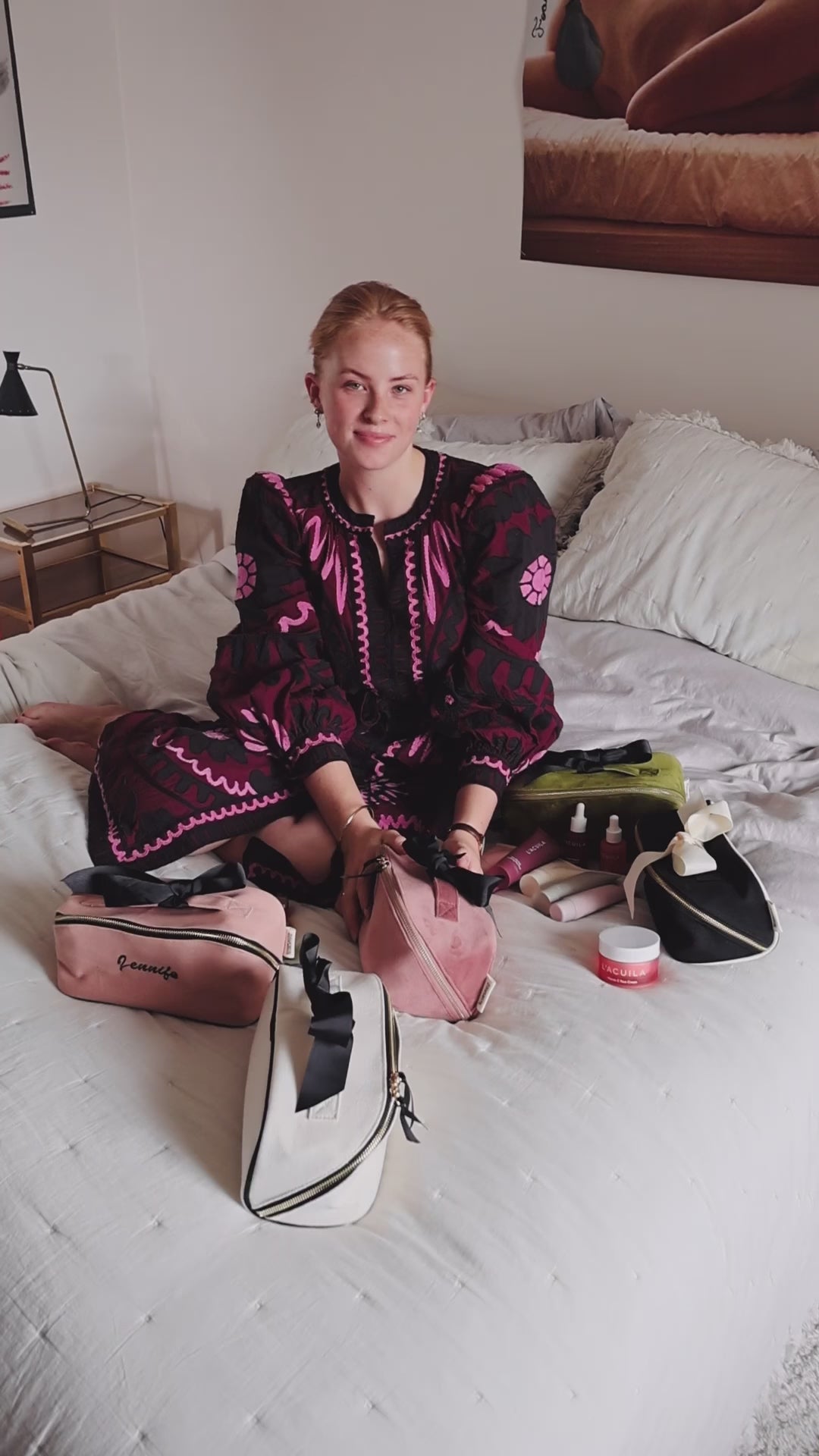 Woman sitting on a bed with Bag-all makeup and toiletry organizers, including the Accordion Box in Pink/Blush. Stylish and practical beauty storage