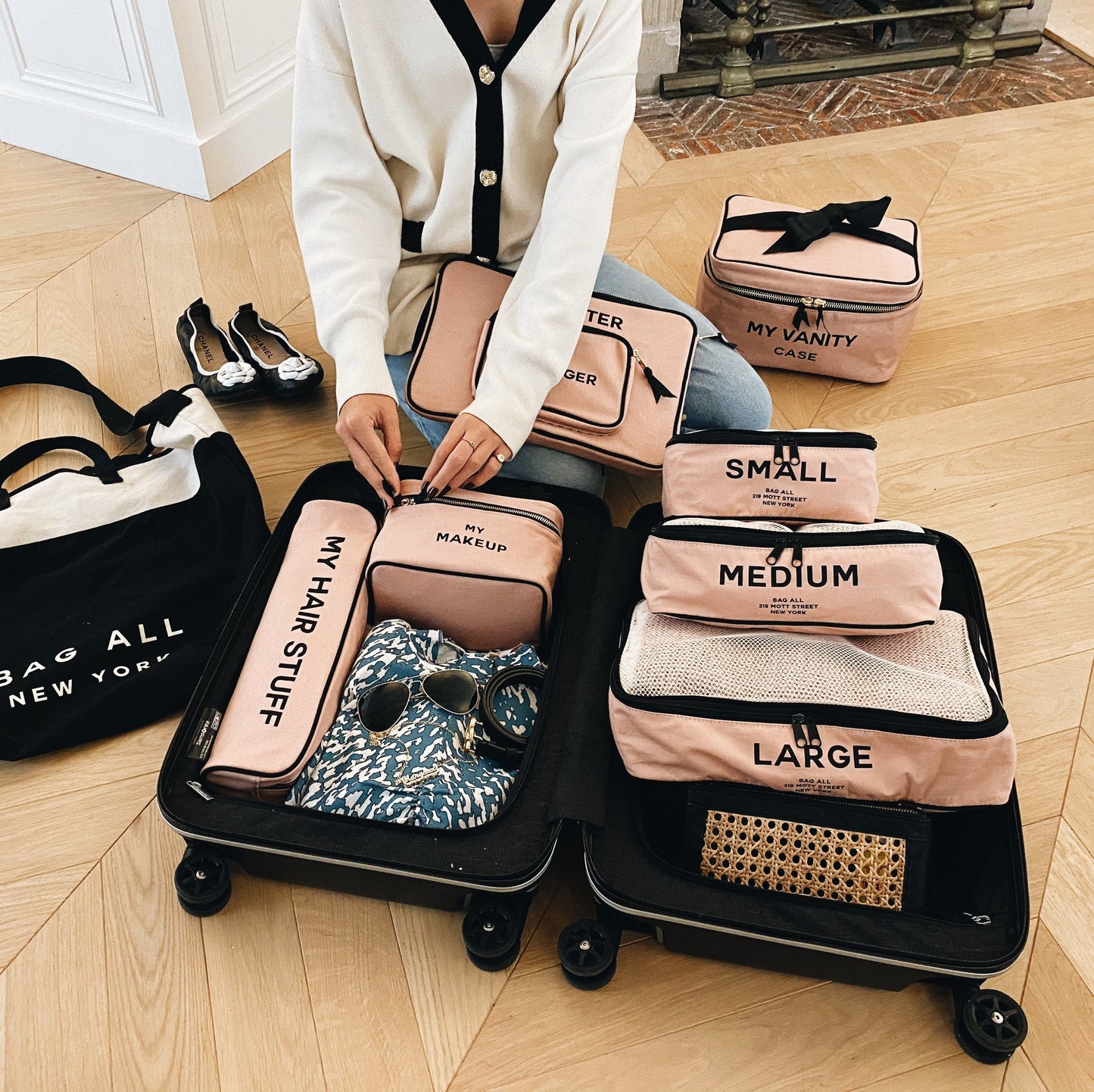 A suitcase full of pink packing cubes, vanity cases, hair stuff cases and computer case in pink.  