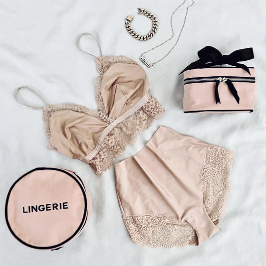 Bag-all Round Lingerie Case in blush pink with black text, shown with matching pink lace lingerie set and accessories on white background