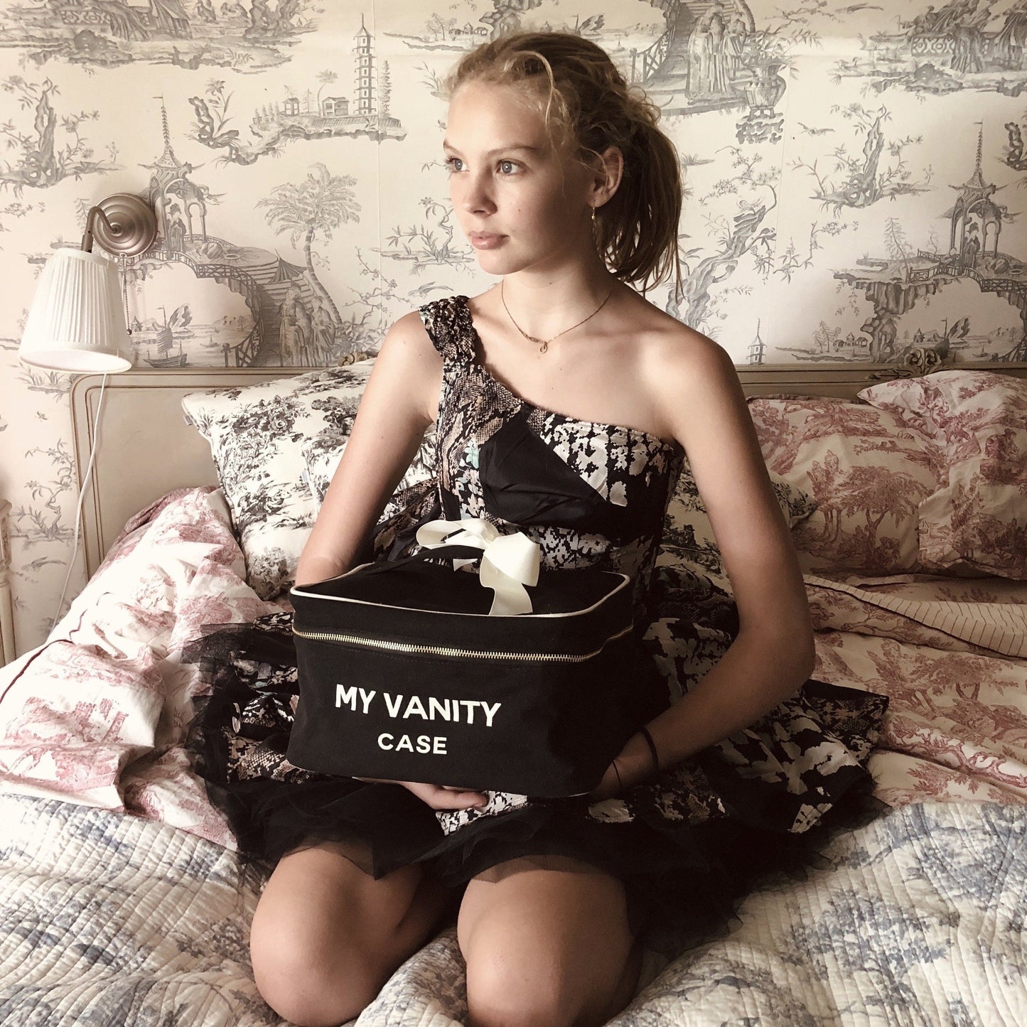 Bag-all My Vanity Large Beauty Box in classic black, featuring elegant white text, waterproof lining and grosgrain ribbon, shown on vintage-style toile patterned sofa background