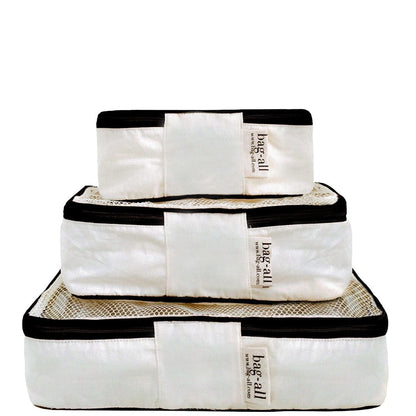 Bag-all Cotton Packing Cubes 3-pack in cream with black trim, featuring mesh panels and convenient organization for travel. Stackable design in different sizes for efficient suitcase storage.