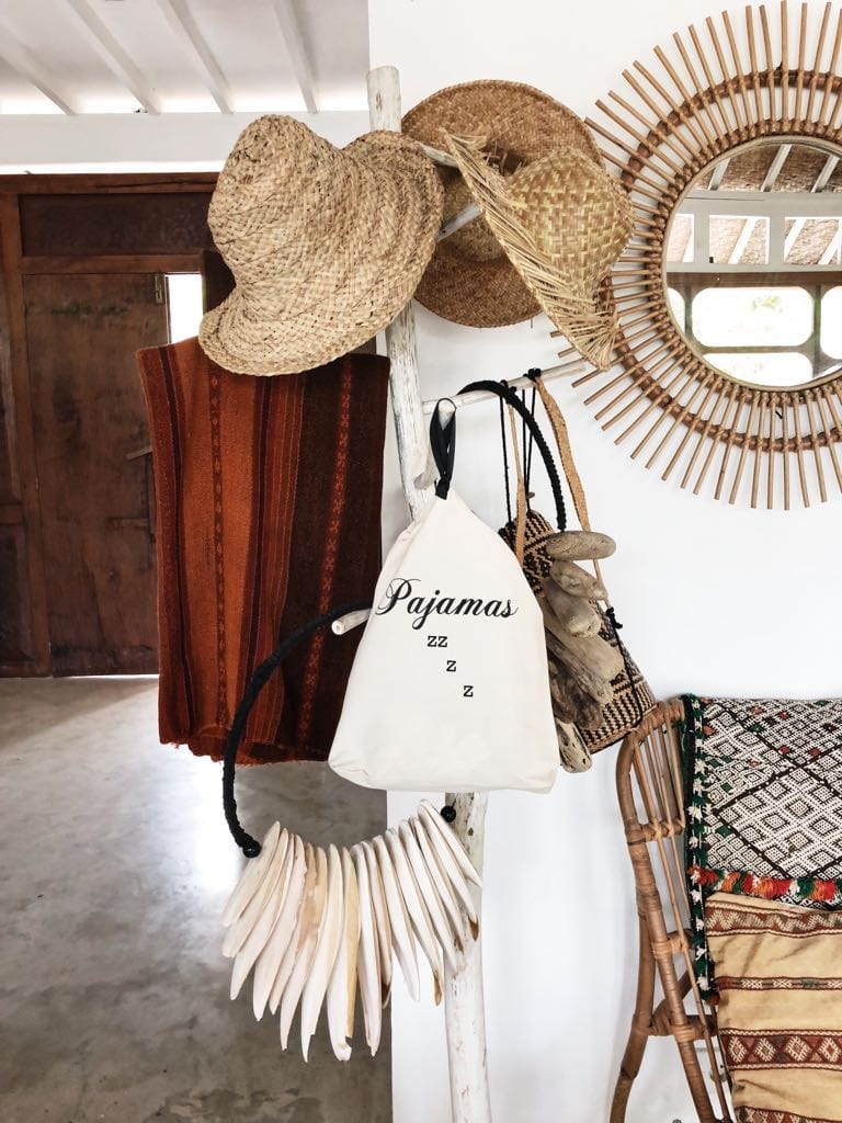 A home with a clothing rack with hats, blankets and a pajamas bag hanging off the hooks. 